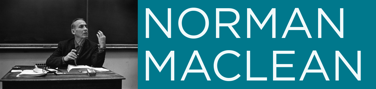 Norman MacLean seated in a classroom at a desk with an open book and some papers in front of him.